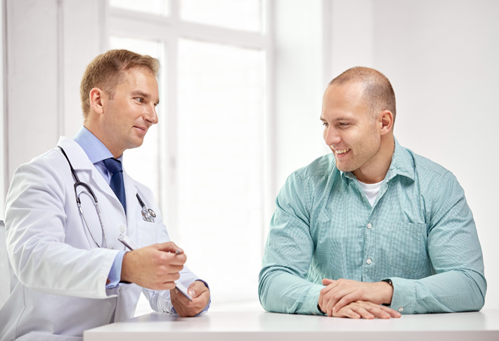 A doctor holds a tablet computer and discusses medical care options with a patient