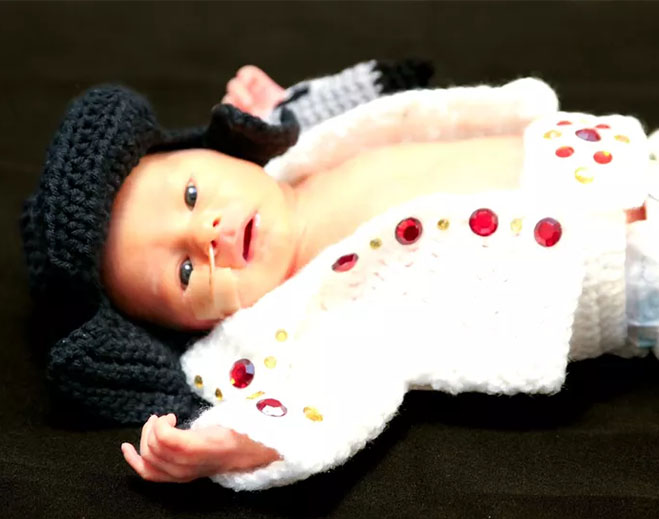 Newborn wearing crocheted Elvis‑style outfit